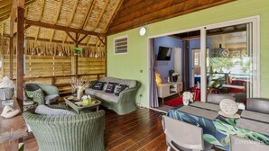 A cozy room with wicker furniture, a wooden ceiling, and a view of the outdoors. - Fare Oaoa · on the Haapiti surf pass, sleeps 4 (Moorea)