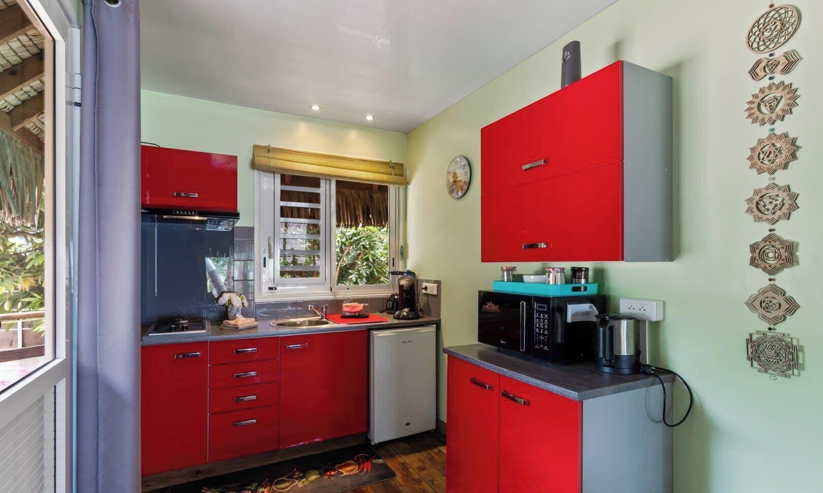 A compact kitchen with red cabinets, a microwave, and a coffee maker.