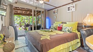 Een slaapkamer met een bed, een plafondventilator, een nachtkastje en uitzicht op het landschap.