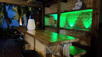 Un'area con bancone in legno, una statua di Buddha, illuminazione ambientale verde e un pannello decorativo in materiali tessili.