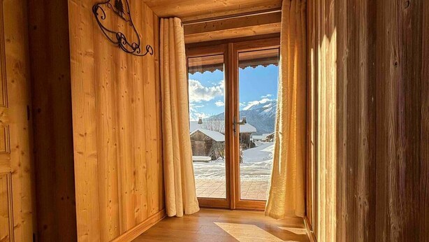 Interior de madera con un amplio ventanal corredero que da a un área exterior nevada.