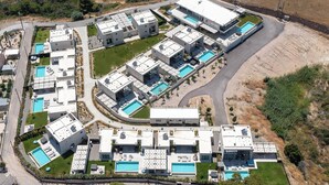 Vista aérea de un moderno complejo residencial con varios edificios, piscinas y zonas ajardinadas.