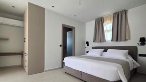 Un dormitorio con cama, armario, escritorio y ventana con cortinas.