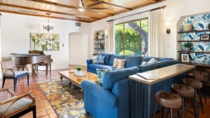 Ein Wohnzimmer mit blauem Sofa, Holztisch und Essbereich inklusive Klavier.