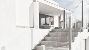 Una escala moderna amb baranes de vidre que condueix a un espai interior obert.