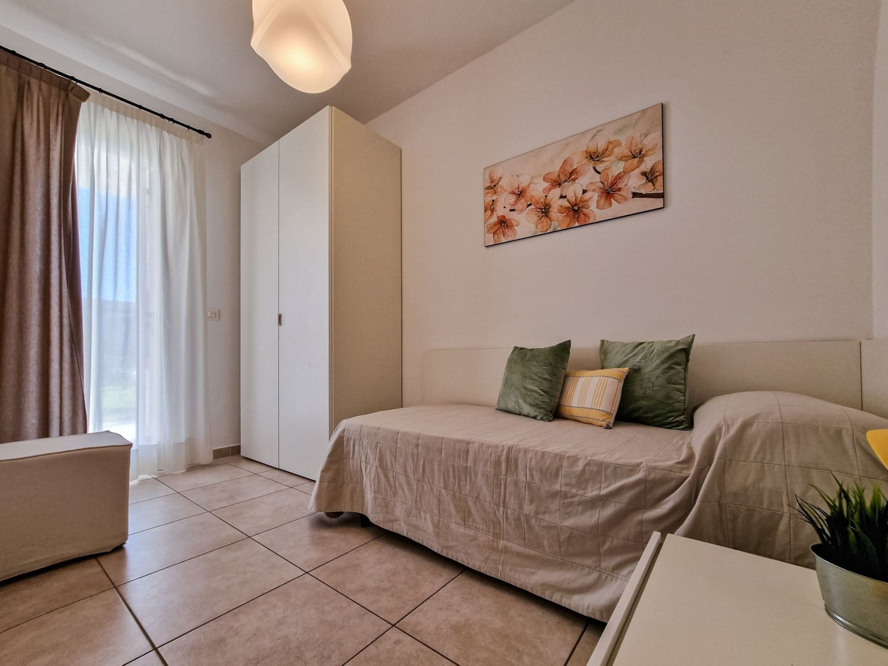 Une chambre moderne avec un lit, un canapé, un bureau et une fenêtre avec des rideaux.