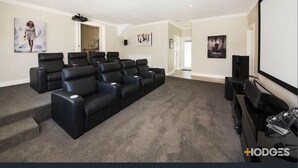 Ein Heimkino mit großer Leinwand, mehreren Liegesesseln und Teppichboden.