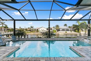 Una piscina con una vista despejada del entorno, incluyendo una casa y palmeras.