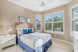 Un dormitorio con cama, mesita de noche y ventilador de techo.