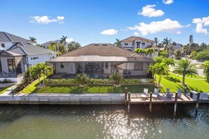 A residential property with a dock, a swimming pool, and a well-maintained lawn.