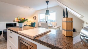 Eine moderne Küche mit Granitwerkstein, Schneidebrett aus Holz, einem Messerblock und einem eingebauten Backofen.