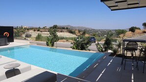 Ein Schwimmbecken mit Liegestühlen, einem Tisch und Blick auf die umliegende Landschaft.