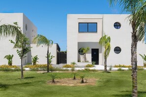 A modern building with a flat facade, circular windows, and a small entrance.