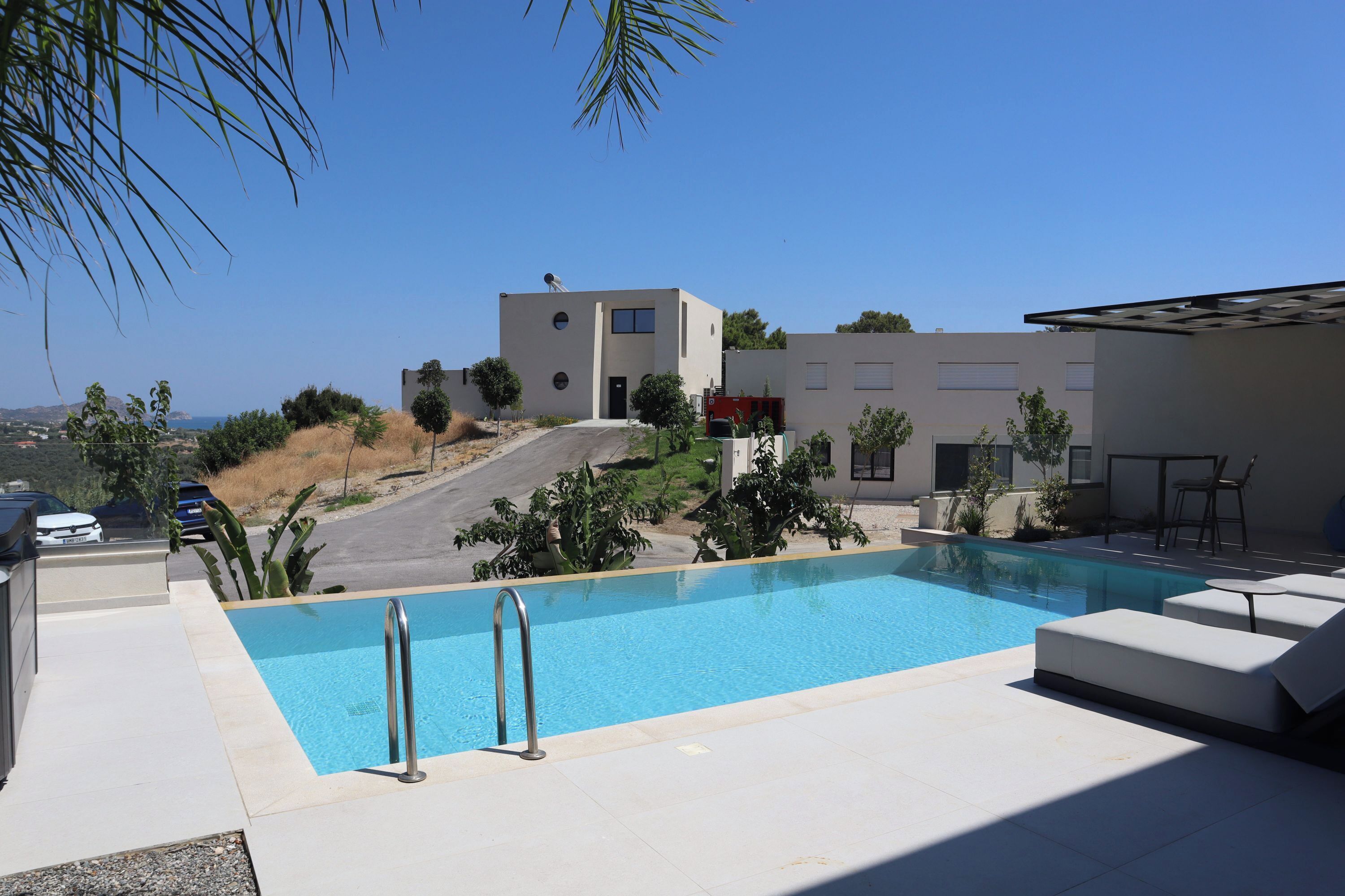 A modern pool area with a clear blue pool, a metal ladder, and a white lounge chair.