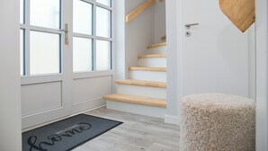 A modern interior with a staircase, a wooden heart-shaped decoration, and a welcome mat. - Möwenstraße 9 Haus 3 Inkl. Wlan (Grömitz)