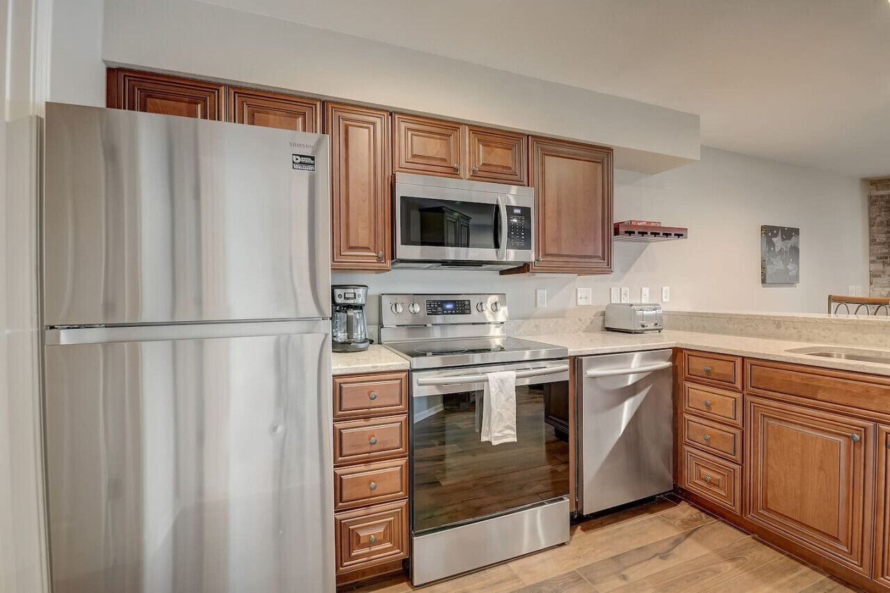 A modern kitchen with stainless steel appliances, wooden cabinets, and a granite countertop.
