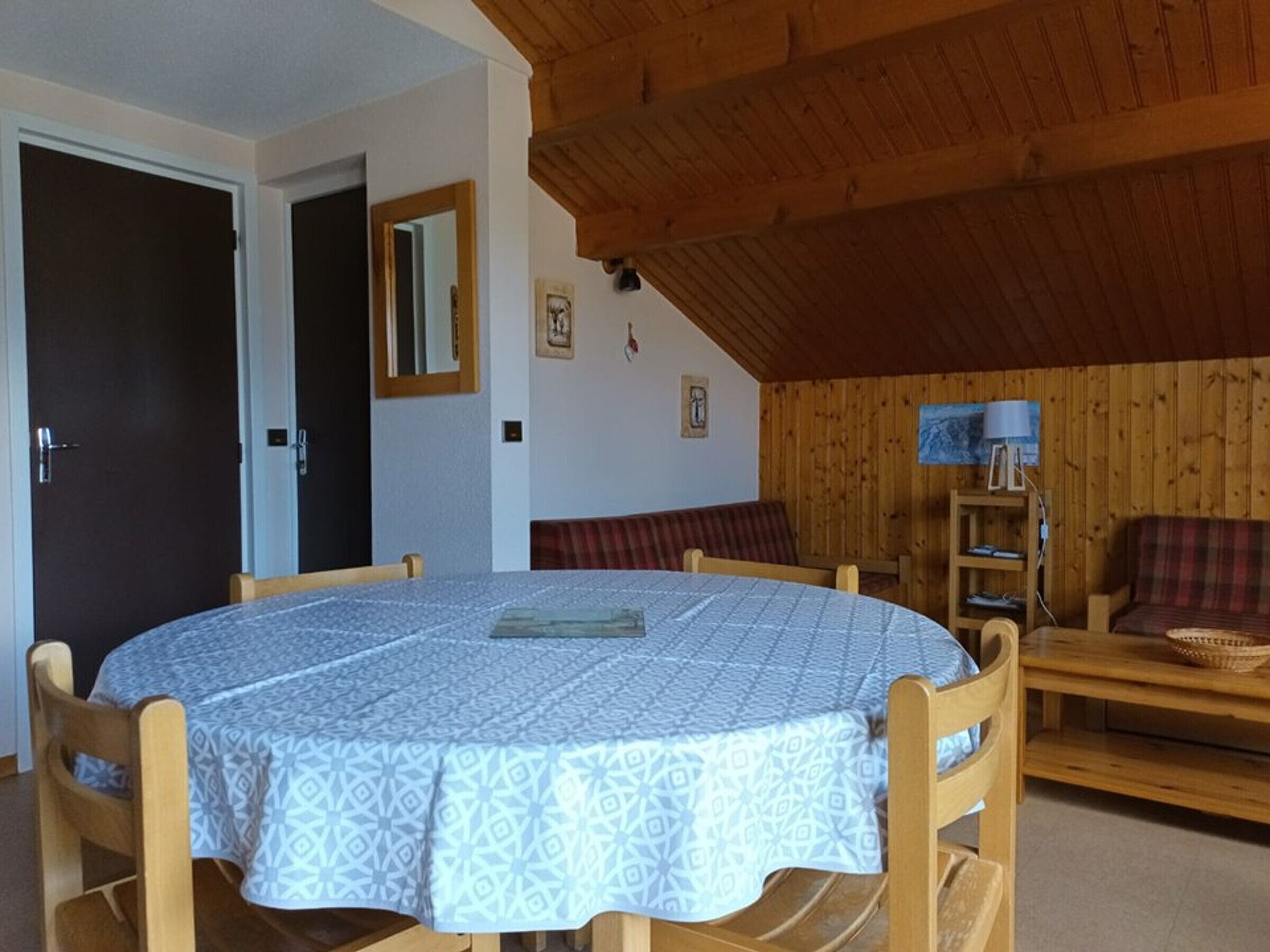 Une pièce chaleureuse avec une table ronde, des chaises en bois, un banc et un plafond en bois.