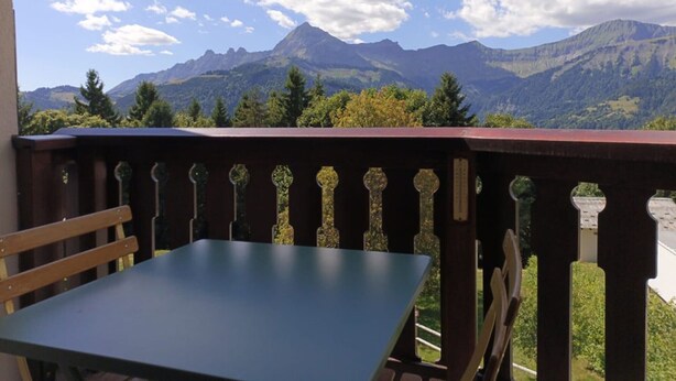 A balcony with a table and chairs, overlooking a mountainous landscape with trees and a clear sky. - Apartment for 4, near slopes and shops, Crest-Voland (Crest-Voland)