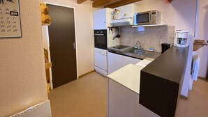 A compact kitchen with a microwave, oven, and sink. There is a calendar on the wall and a door to the left. - Apartment for 4, near slopes and shops, Crest-Voland (Crest-Voland)