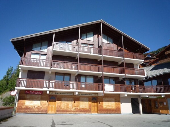 A multi-story building with balconies, a bar restaurant, and a sign for 'Le Belvedere'.