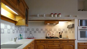 Una cocina con armarios de madera, encimera blanca, estufa y salpicadero de azulejos.