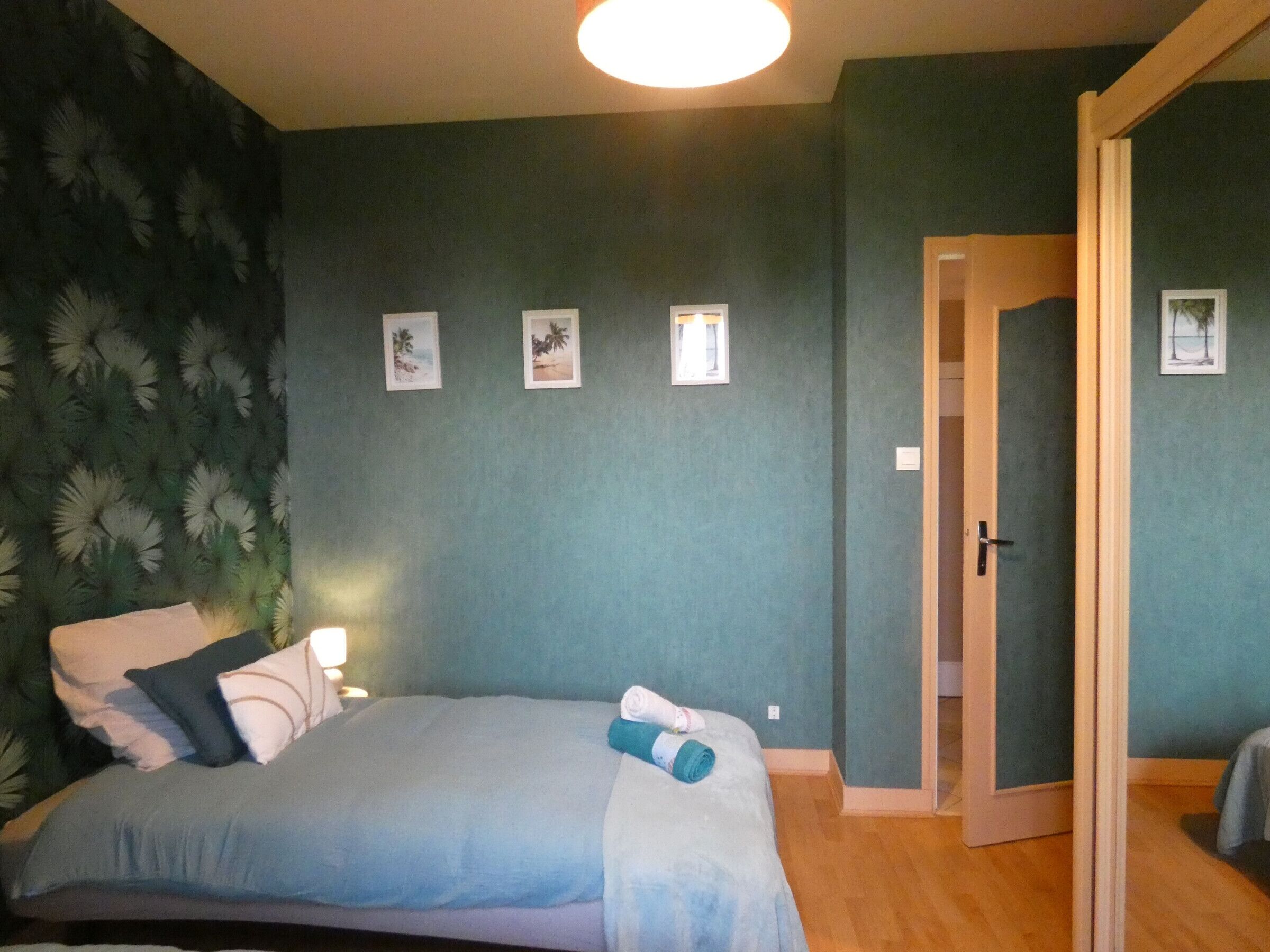 A bedroom with a bed, a nightstand, a lamp, and a door.