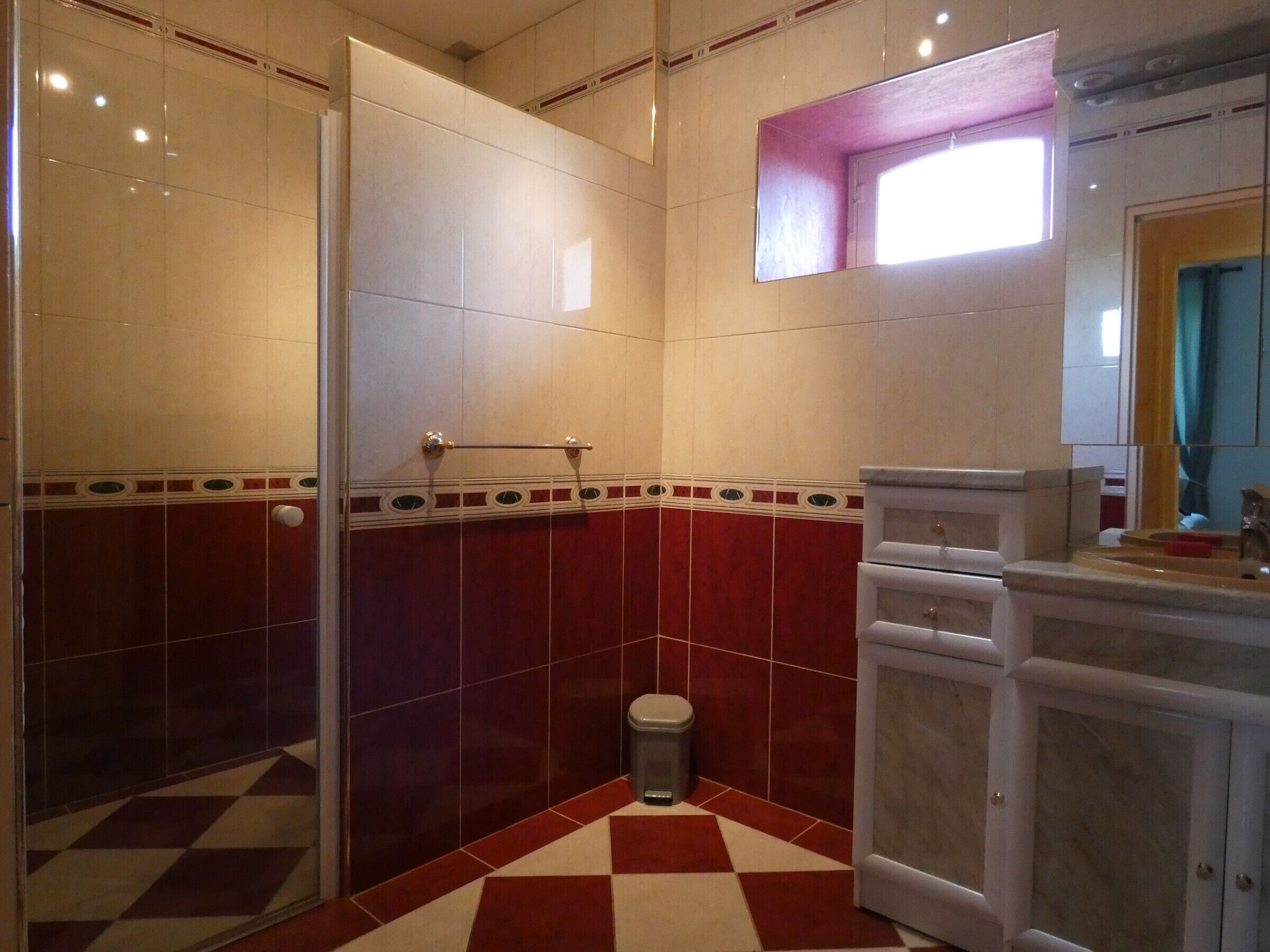 Un baño con piso a cuadros, un inodoro, un lavamanos y un espejo.