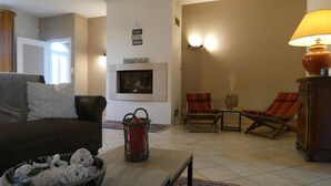Una sala de estar con chimenea, dos sillones, un sofá, una mesa de centro y una lámpara.