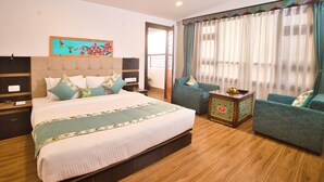 Un dormitorio con una cama grande, un sofá, una mesita con fruta y un cuadro en la pared.