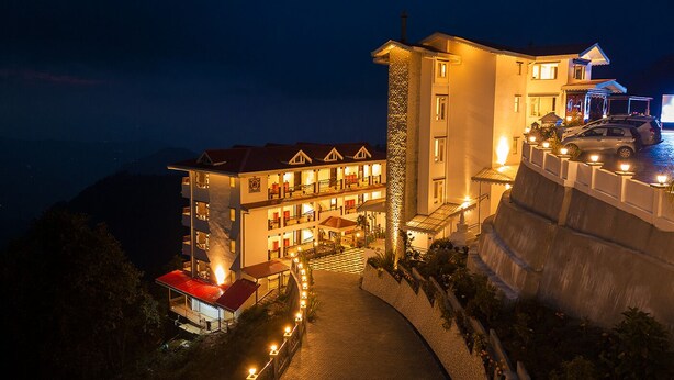 Un hotel de varios pisos con un patio central, balcones y vistas del paisaje circundante.