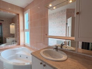 Un baño con una bañera grande, un lavabo y un espejo.