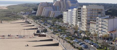 Un paisaje urbano costero con playa, edificios altos y un estacionamiento.
