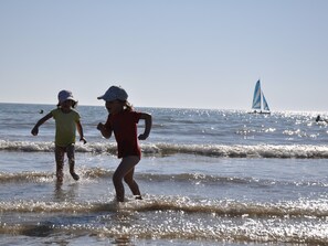 Two children playing in the water with a sailboat in the background. - T2+ Cabin Apartment with Pool and Parking in Saint-Jean-de-Monts (Saint-Jean-de-Monts)