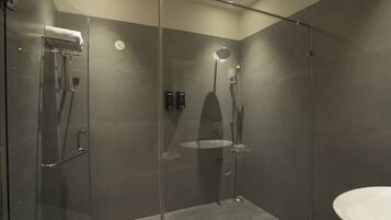 Un baño moderno con cabina de vidrio, cabezal de ducha manual y grifo empotrado.