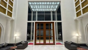 Un hall d’entrée spacieux, doté d’une grande porte vitrée, d’un sol en marbre et de meubles modernes.