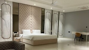 Une chambre moderne avec un grand lit, un coin salon comprenant un canapé et une table basse, ainsi qu’un bureau avec une chaise.