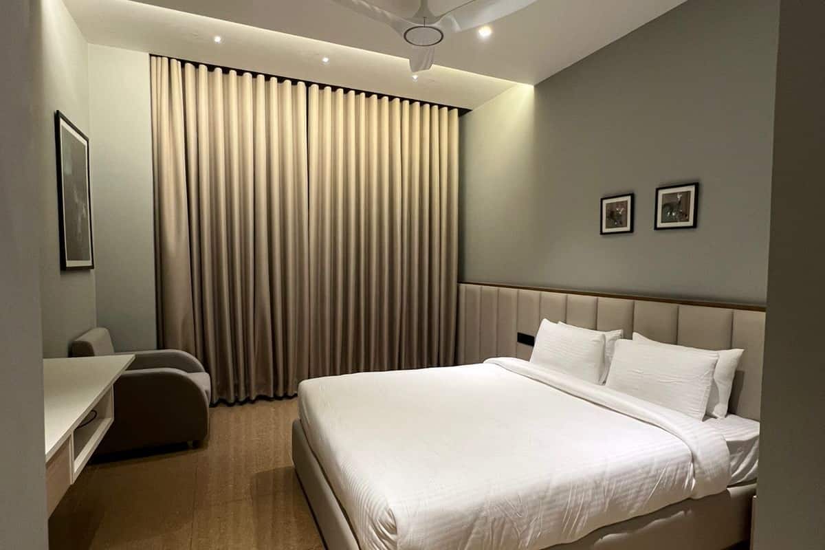 A modern hotel room with a large bed, a desk, and a chair.