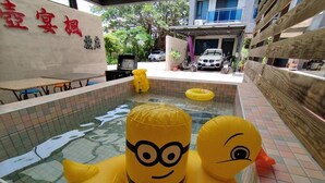 Un espace piscine avec des bouées gonflables à l’effigie des Minions, un panneau avec des caractères chinois et une voiture garée.