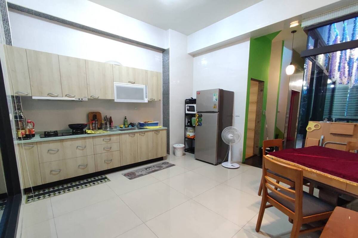 A compact kitchen with wooden cabinets, a microwave, a refrigerator, and a dining area with a table and chairs.