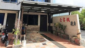 Un immeuble à plusieurs étages doté d’une entrée couverte, d’une enseigne avec des caractères chinois et d’une moto garée.