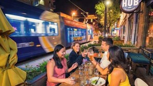 Un grupo de personas cenando al aire libre de noche, con un tren pasando.