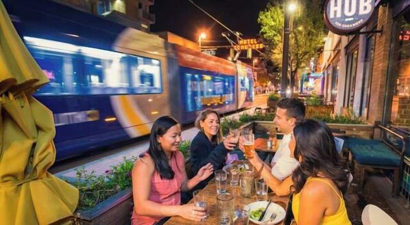 A group of people dining outdoors at night with a train passing by.
