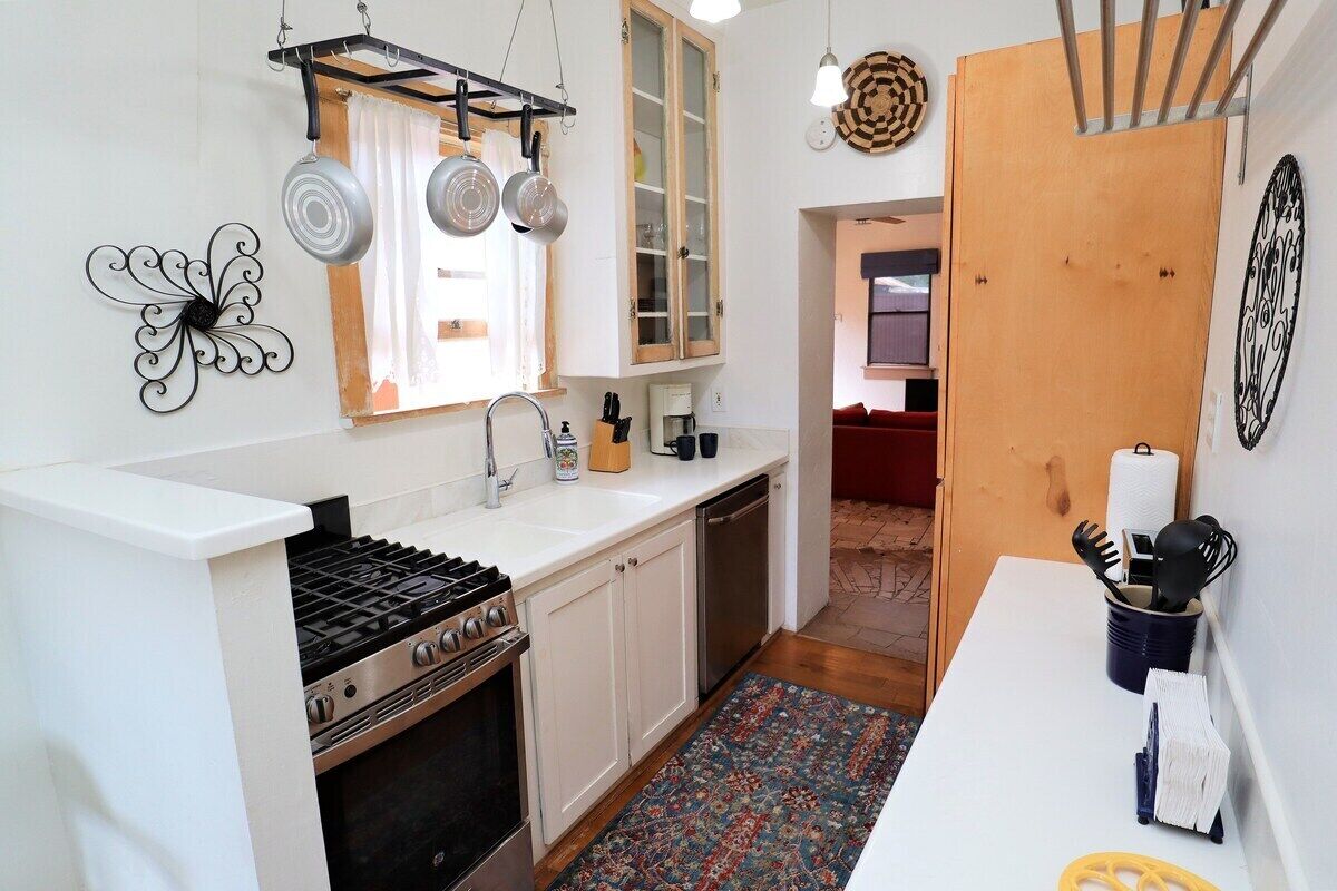 A kitchen with a gas stove, white cabinets, a sink, and a patterned rug.