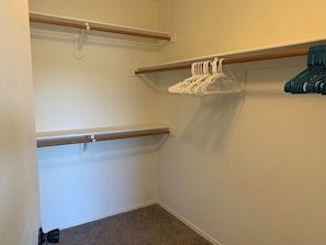 A small, enclosed closet with two wooden rods, one with white hangers and one with blue hangers. - Thunder Ridge (Tucson)