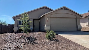 A two-story house with a garage, a small tree in the front yard, and a clear blue sky. - Thunder Ridge (Tucson)