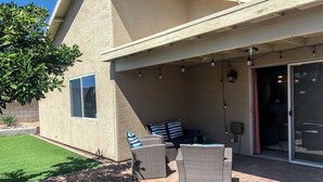 An outdoor patio with wicker furniture, a glass door entrance, and a small window. - Thunder Ridge (Tucson)