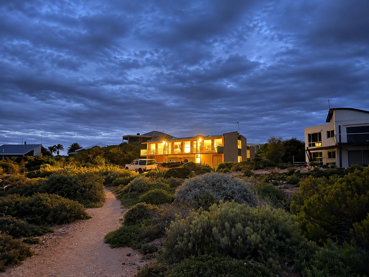 A modern two-story house with a visible driveway and surrounding vegetation.