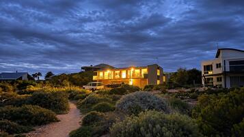 A modern two-story house with a visible driveway and surrounding vegetation.