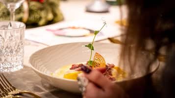 A dining table with a plate of food, a glass of water, and a fork.
