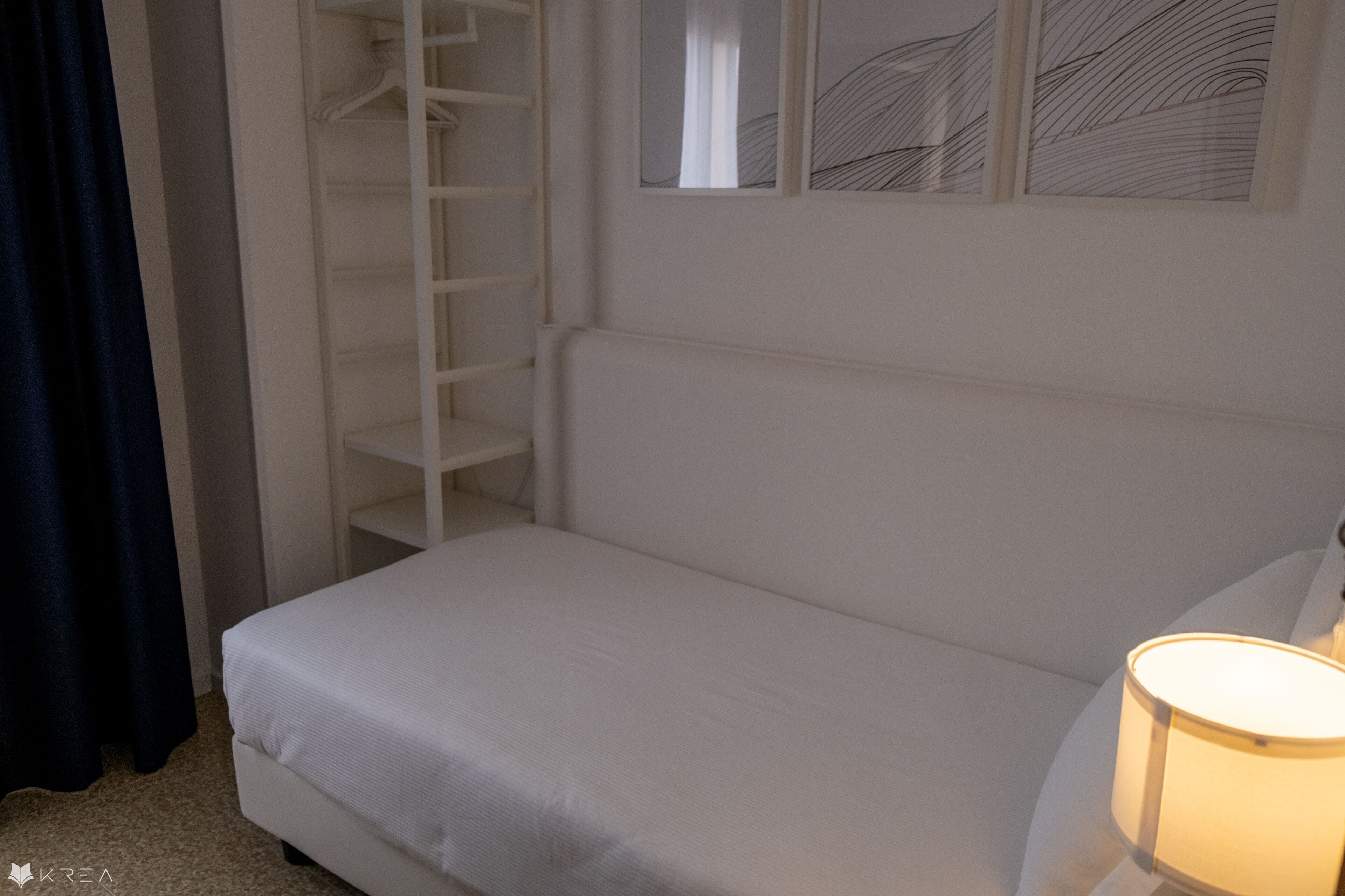Ein Schlafzimmer mit einem Bett, einem Kleiderschrank und einem an der Wand befestigten Regal.